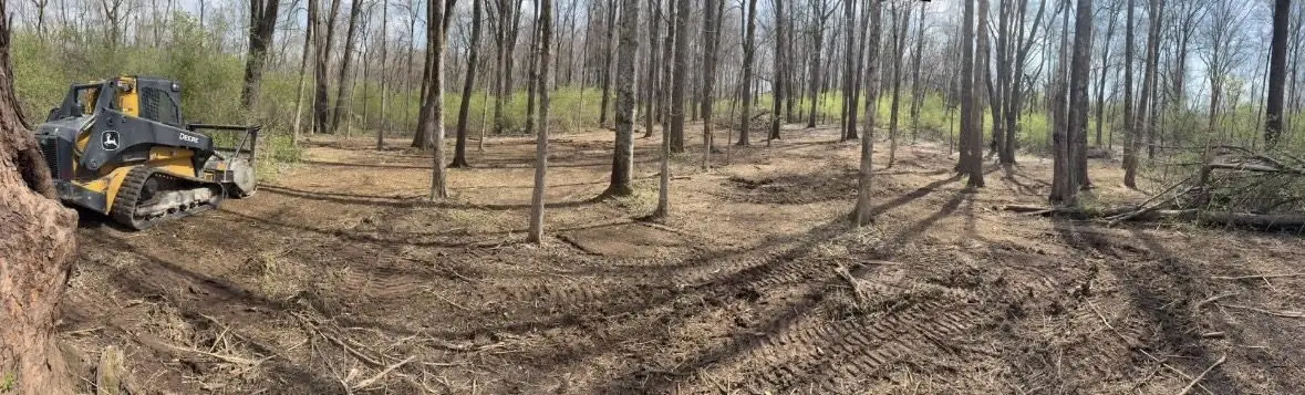 Tractor working a freshly prepared plot inside a wooded property